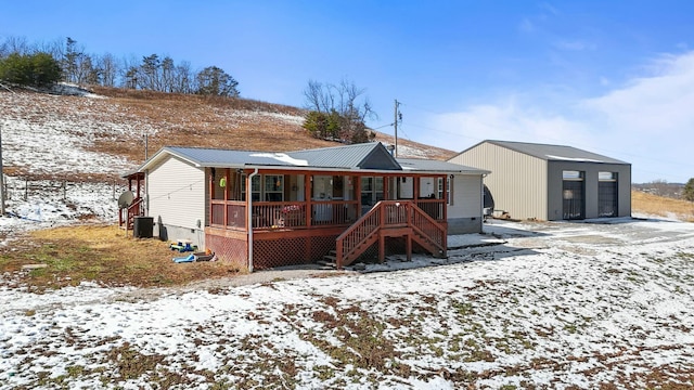 snow covered back of property with a porch, crawl space, metal roof, and stairway