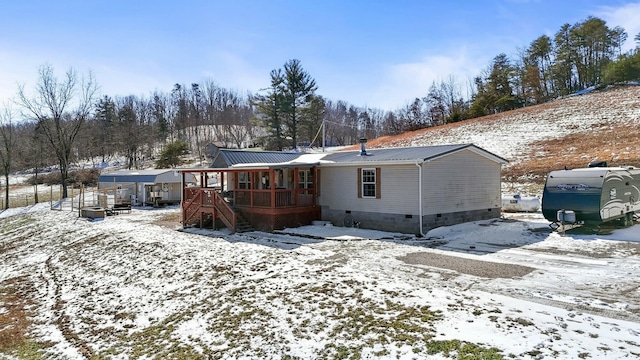 snow covered rear of property featuring stairs, metal roof, and crawl space