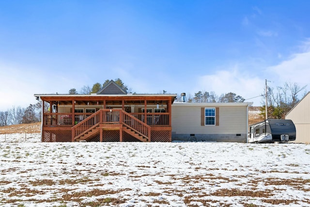 snow covered back of property featuring crawl space, metal roof, and stairs