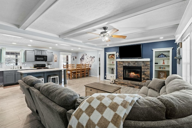 living room featuring a wealth of natural light, beamed ceiling, and a textured ceiling