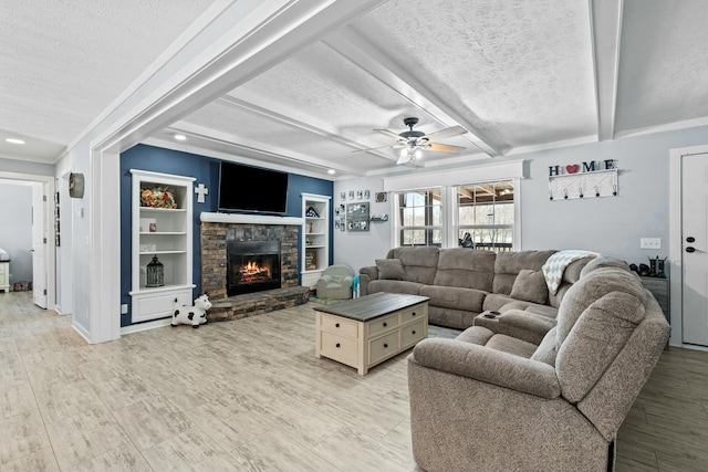 living area with beam ceiling, a textured ceiling, and a stone fireplace