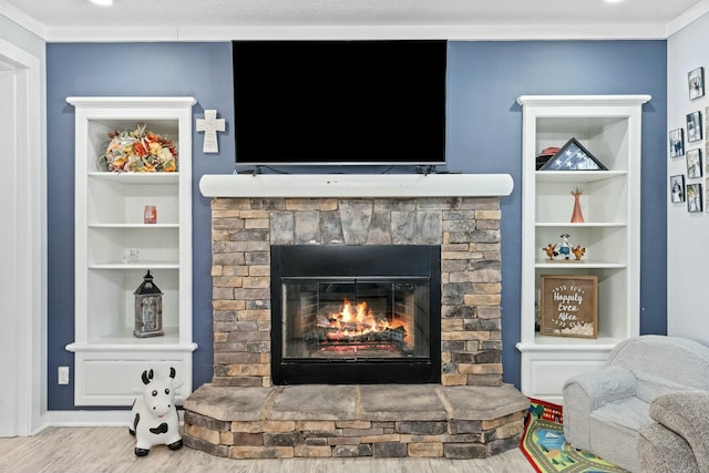 interior details featuring ornamental molding, wood finished floors, a glass covered fireplace, and built in features