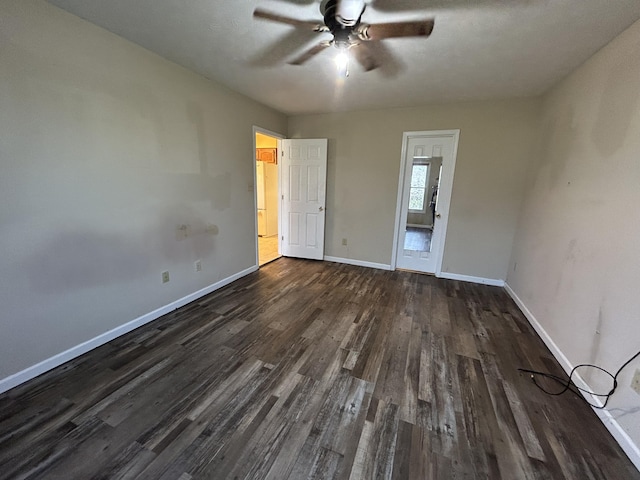 unfurnished bedroom featuring dark wood-style floors, baseboards, and a ceiling fan