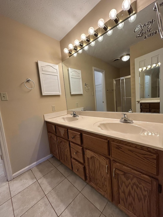 bathroom featuring a textured ceiling, tile patterned flooring, a sink, and a shower stall