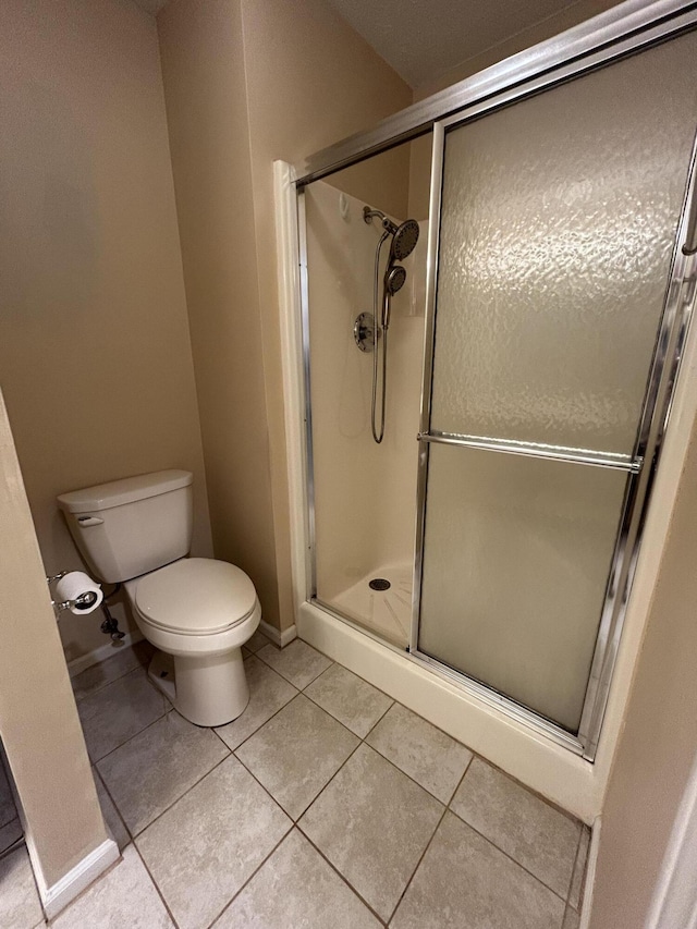 full bath with baseboards, a stall shower, toilet, and tile patterned floors