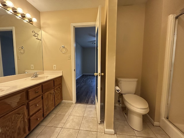 full bath with double vanity, baseboards, toilet, tile patterned floors, and a sink