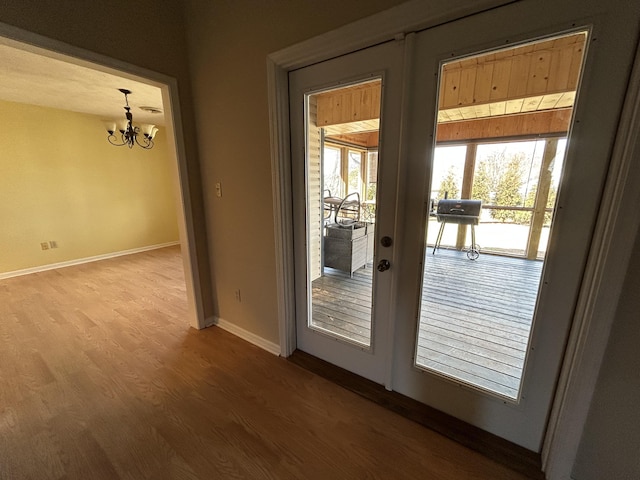 doorway to outside with an inviting chandelier, baseboards, wood finished floors, and french doors