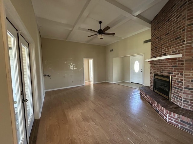 unfurnished living room with visible vents, baseboards, coffered ceiling, wood finished floors, and a brick fireplace