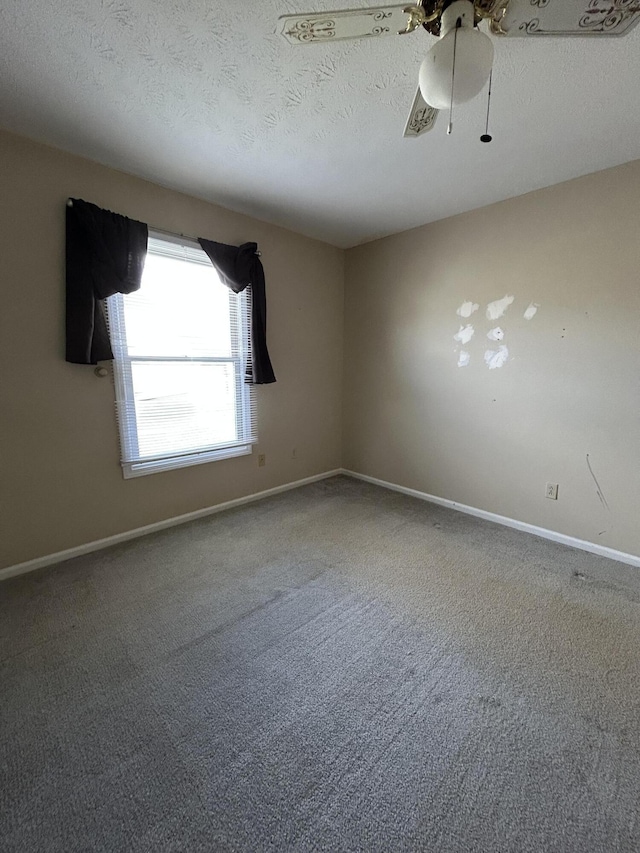 carpeted spare room with a ceiling fan, baseboards, and a textured ceiling