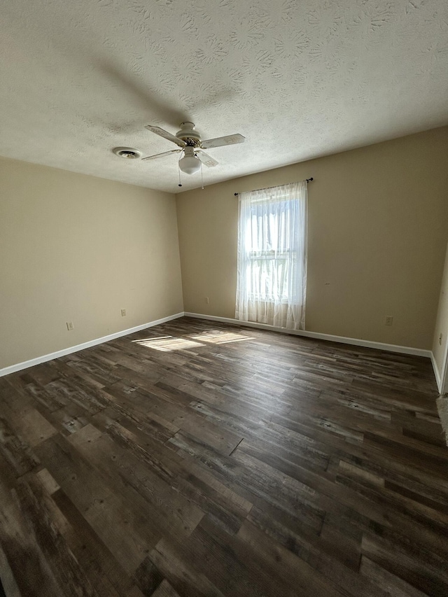 spare room featuring visible vents, dark wood finished floors, baseboards, and ceiling fan