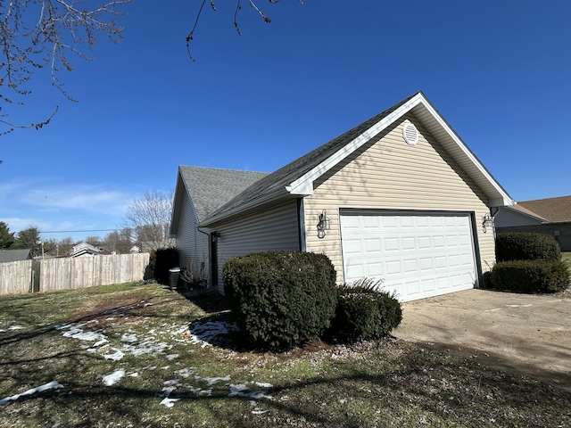 view of property exterior with a garage, concrete driveway, roof with shingles, and fence