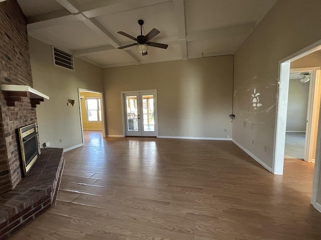 unfurnished living room featuring baseboards, visible vents, wood finished floors, french doors, and a brick fireplace