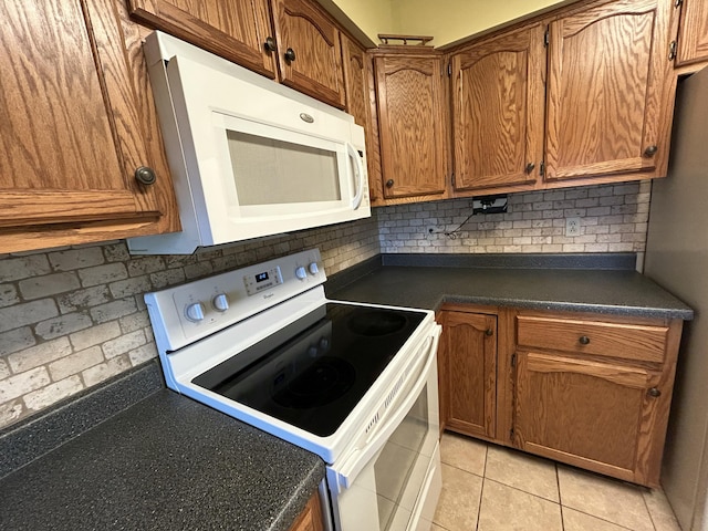 kitchen featuring dark countertops, white appliances, brown cabinets, and backsplash