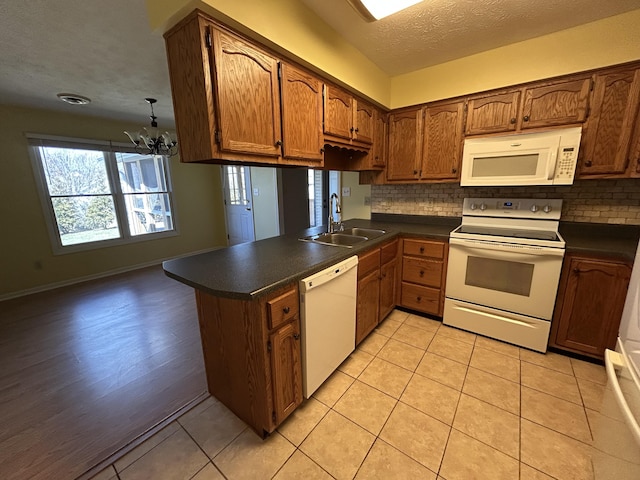 kitchen with dark countertops, white appliances, a sink, and decorative backsplash