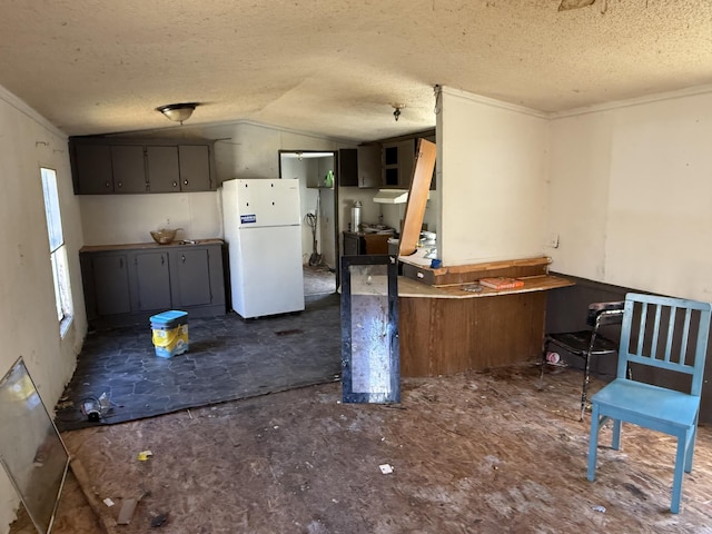 kitchen featuring lofted ceiling, crown molding, a textured ceiling, and freestanding refrigerator