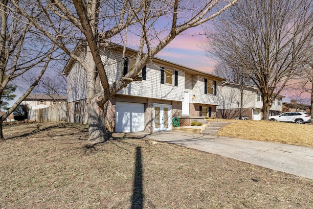 bi-level home with a garage, concrete driveway, and brick siding