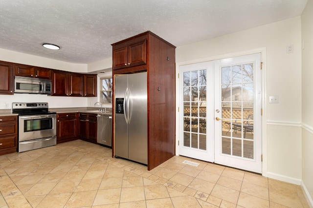 kitchen with stainless steel appliances, a sink, visible vents, light countertops, and french doors