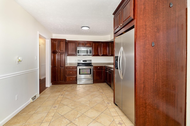 kitchen featuring baseboards, appliances with stainless steel finishes, light countertops, and a textured ceiling