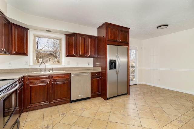 kitchen featuring light countertops, appliances with stainless steel finishes, light tile patterned flooring, a sink, and baseboards