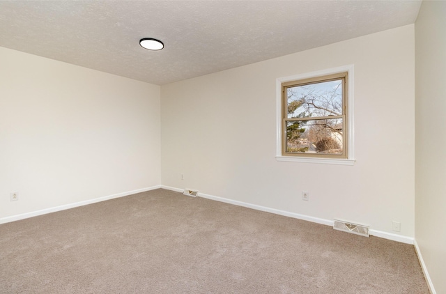 unfurnished room with a textured ceiling, carpet floors, visible vents, and baseboards