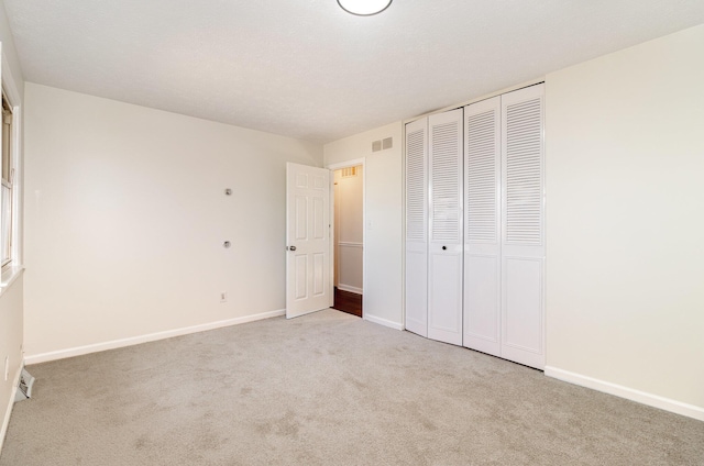 unfurnished bedroom featuring carpet, a closet, visible vents, and baseboards