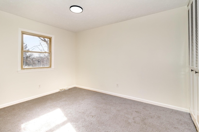 spare room with carpet flooring, visible vents, and baseboards