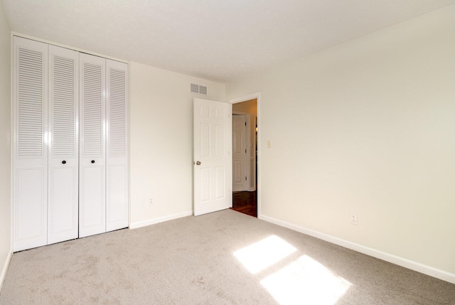 unfurnished bedroom with baseboards, a closet, visible vents, and carpet flooring