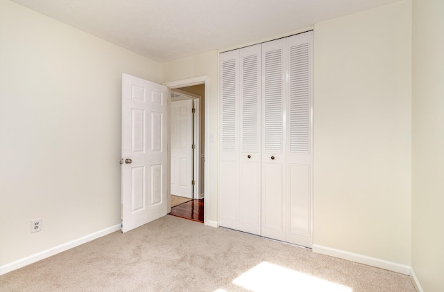 unfurnished bedroom with carpet floors, a closet, and baseboards