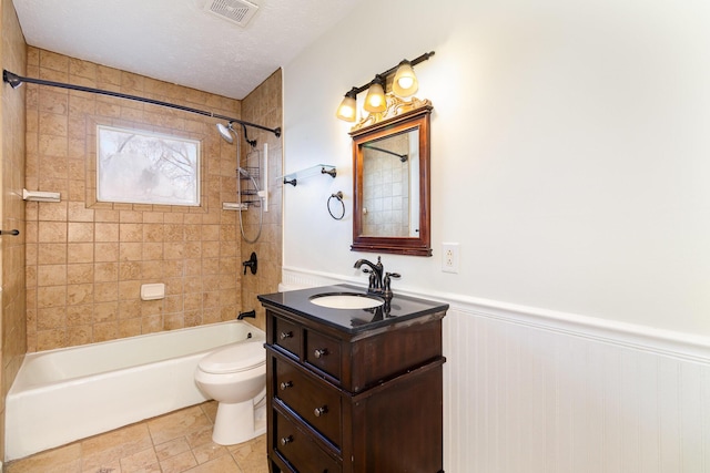 bathroom with shower / washtub combination, a wainscoted wall, visible vents, toilet, and a textured ceiling