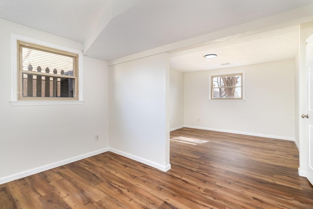 unfurnished room with a textured ceiling, wood finished floors, and baseboards