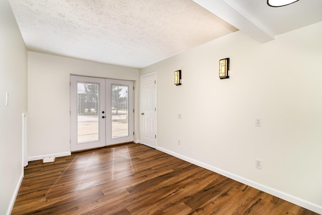 spare room featuring french doors, a textured ceiling, wood finished floors, beamed ceiling, and baseboards