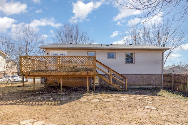 rear view of property with brick siding, stairway, fence, and a wooden deck