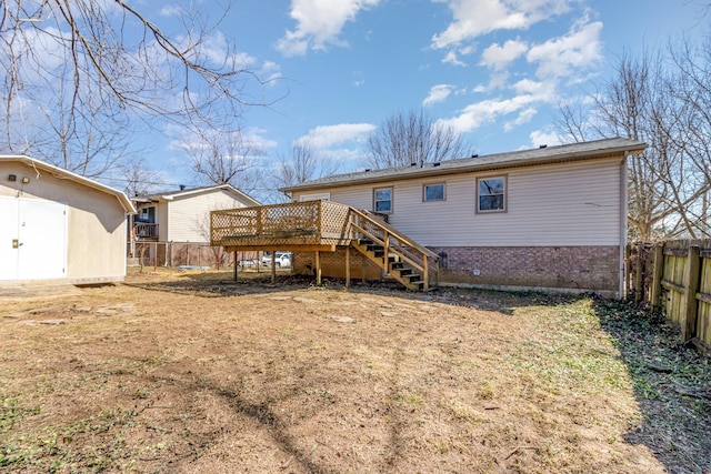 rear view of house featuring a fenced backyard, stairway, a deck, and brick siding