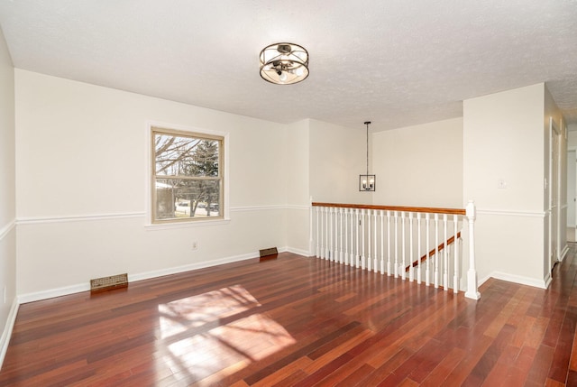 unfurnished room featuring a textured ceiling, baseboards, and wood finished floors