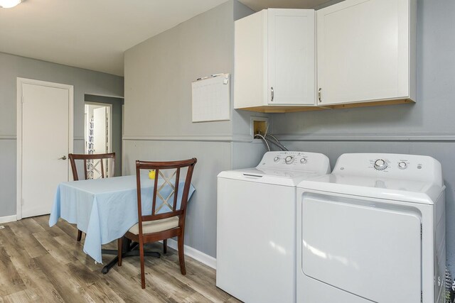 clothes washing area with baseboards, cabinet space, light wood-style flooring, and washer and clothes dryer