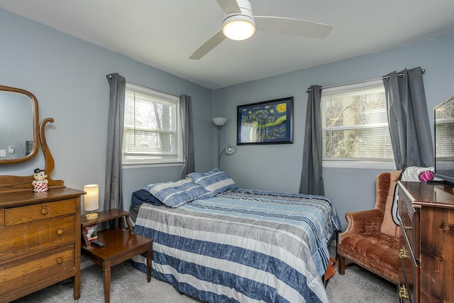 carpeted bedroom with a ceiling fan and multiple windows