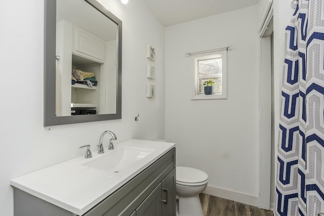 bathroom featuring toilet, wood finished floors, vanity, and baseboards