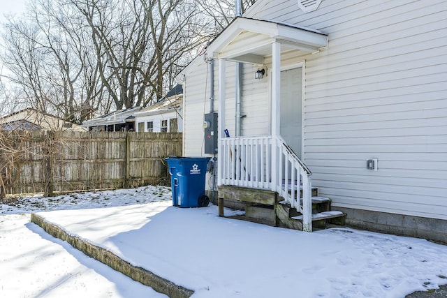 snow covered property entrance with fence