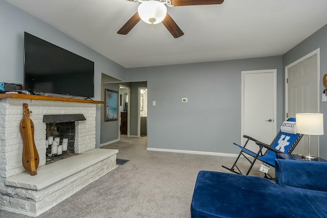 living area featuring ceiling fan, a fireplace, baseboards, and light colored carpet