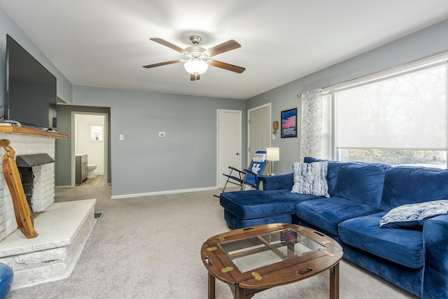 living area with light carpet, ceiling fan, a fireplace, and baseboards