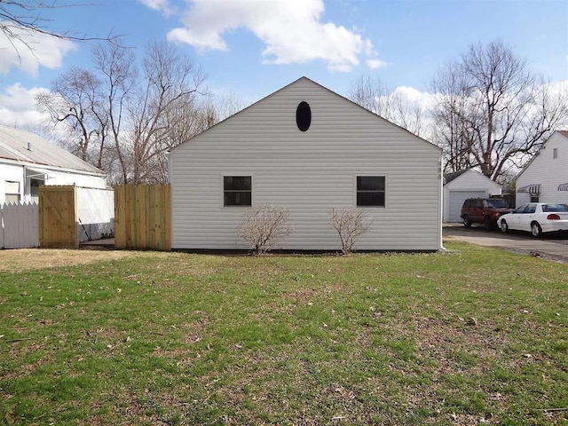 view of home's exterior featuring a yard, fence, and a detached garage