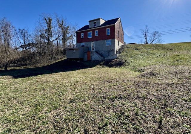 rear view of house with stairs and a lawn