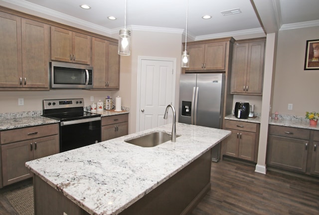 kitchen with stainless steel appliances, hanging light fixtures, a sink, an island with sink, and light stone countertops