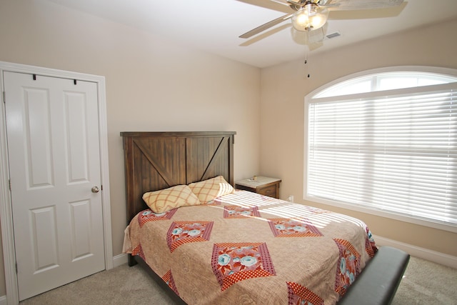 bedroom with light carpet, ceiling fan, visible vents, and baseboards