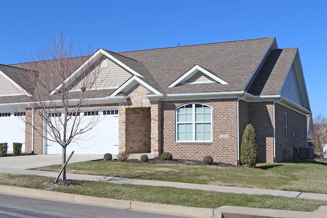 view of front of house with an attached garage, central AC, brick siding, stone siding, and driveway