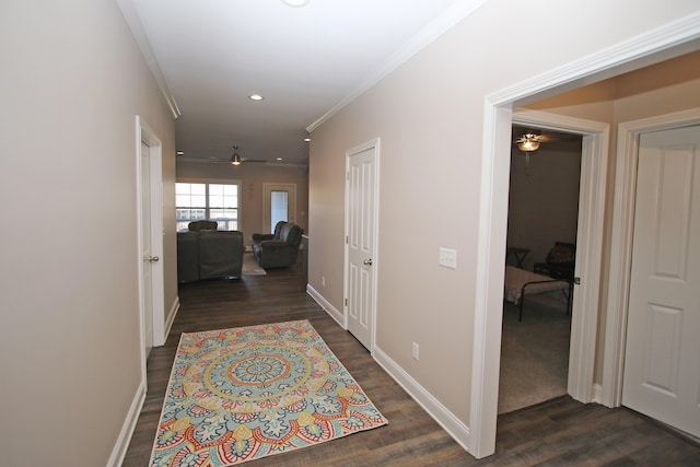 hallway featuring dark wood-type flooring, recessed lighting, crown molding, and baseboards