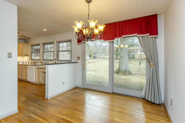 unfurnished dining area with recessed lighting, a notable chandelier, baseboards, and light wood-type flooring