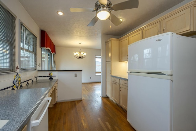 kitchen featuring white appliances, backsplash, dark wood finished floors, and ceiling fan with notable chandelier