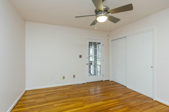 unfurnished bedroom featuring ceiling fan, wood finished floors, visible vents, and baseboards