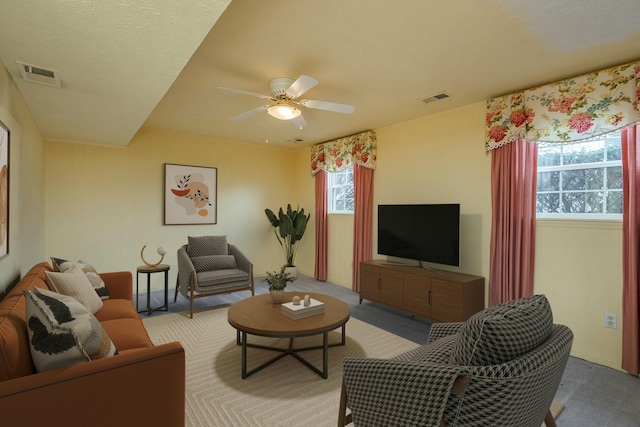 living area with visible vents, carpet flooring, and a ceiling fan